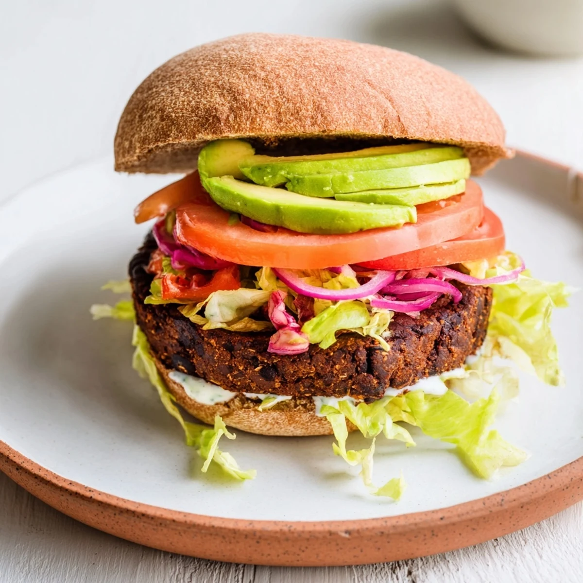 Close-up photo of a delicious black bean burger on a bun, piled high with fresh toppings.
