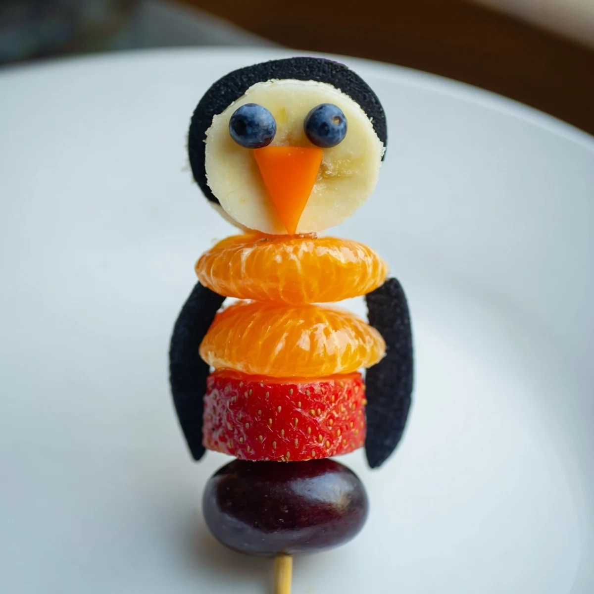 A fun, colorful photo of a Penguin Fruit Skewer Army ready to brighten your kids' party, so delicious!