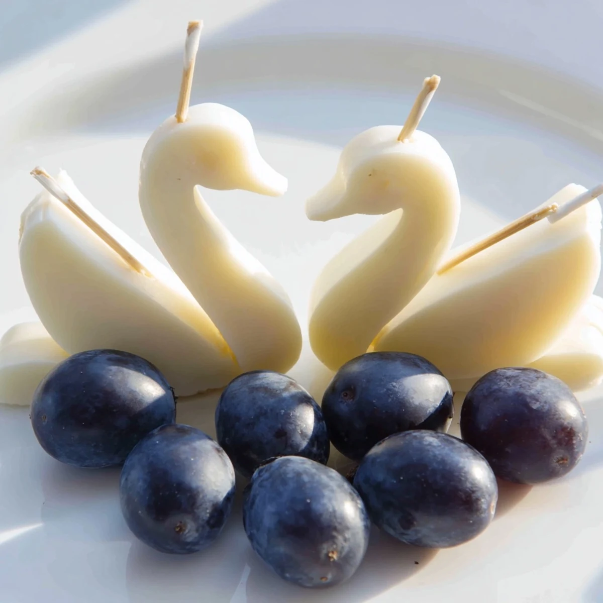 Elegant Swan Lake Board with cheese swans and vibrant blue grapes for a stunning appetizer.