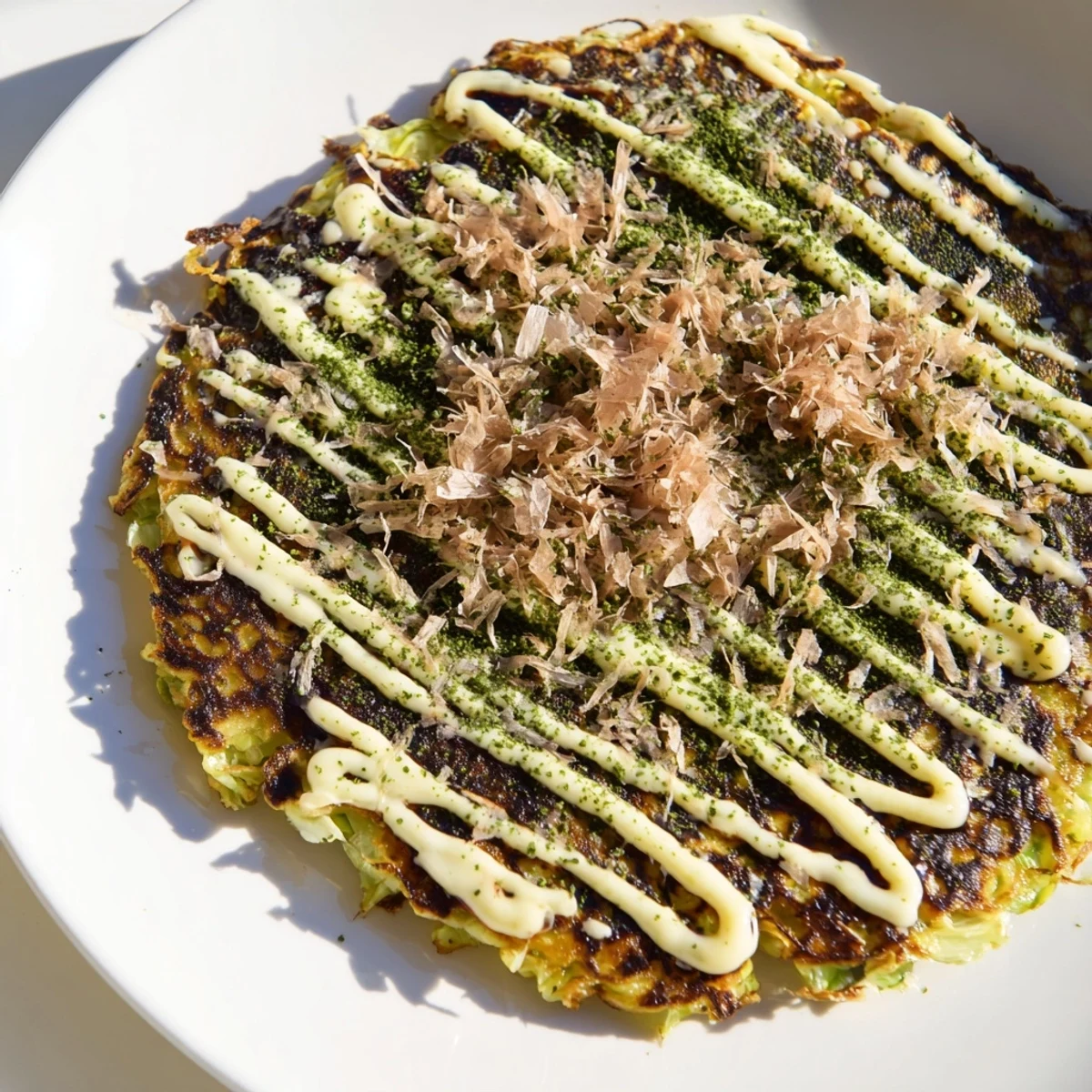 A close-up of fluffy Okonomiyaki pancakes topped with umami sauce, mayo, bonito flakes, and more.