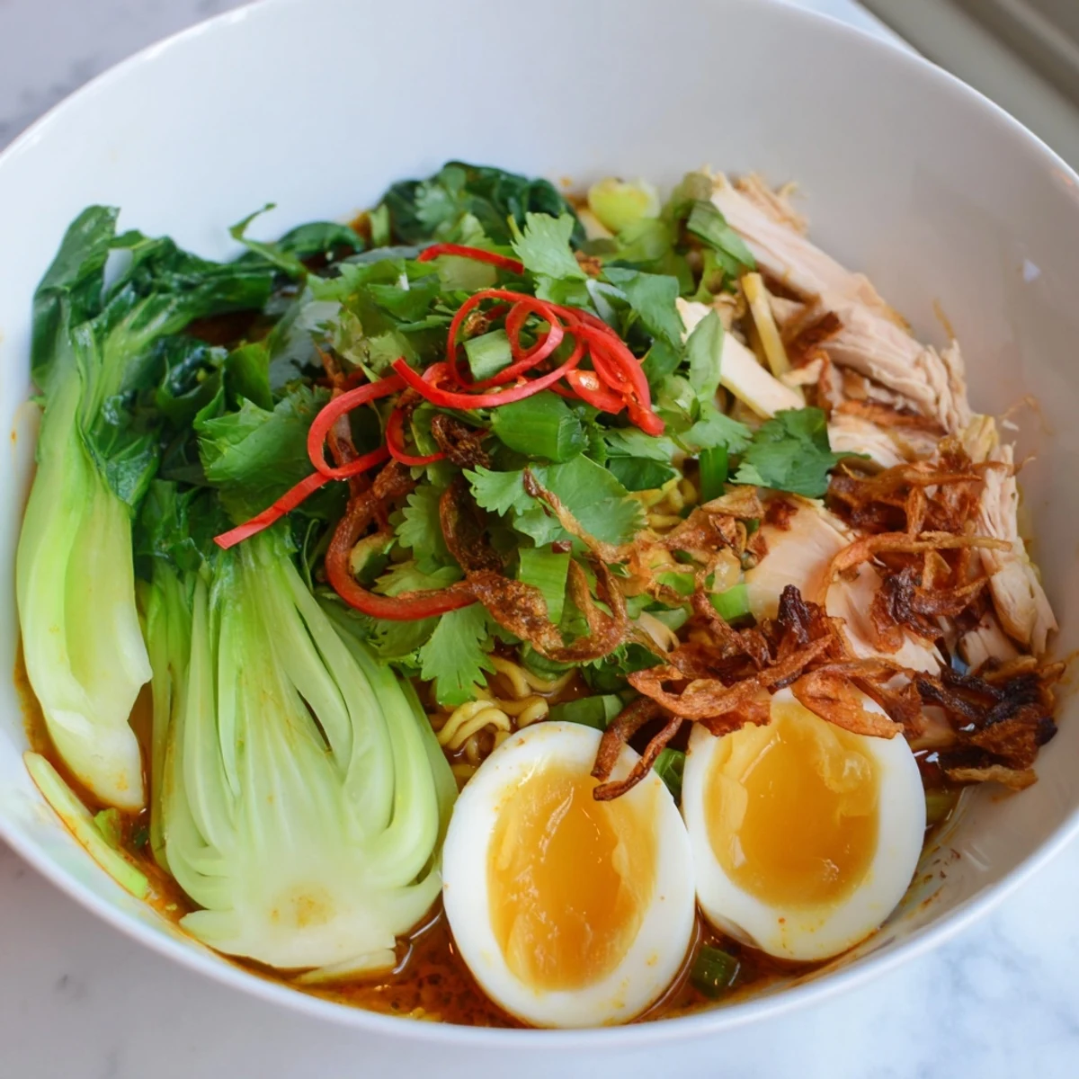 Fragrant Thai Miso Ramen Bowl topped with crispy shallots, scallions, and fresh cilantro leaves.  