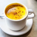 Creamy turmeric and ginger golden milk simmered in a small saucepan, showing golden liquid ready to soothe your throat.  