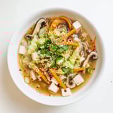 Ginger-Miso Winter Soup served in a rustic ceramic bowl, garnished with scallions and toasted sesame seeds.