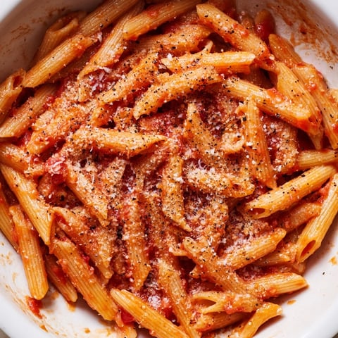 A single serving of easy Microwave Bowl Pasta with Parmesan and marinara sauce, steaming in a ceramic bowl with a fork resting beside it. 