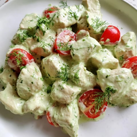 Freshly grilled chicken chunks tossed with avocado ranch dressing, crisp romaine, cherry tomatoes, cucumber, and red onion served in a white bowl.