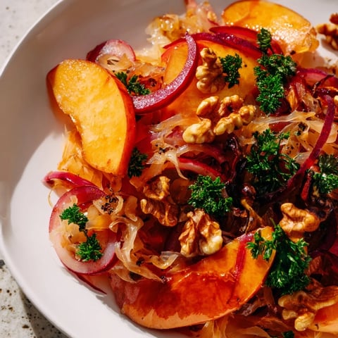 Golden apples and tangy sauerkraut sizzle together in a warm skillet, garnished with fresh parsley and crunchy walnuts for a vibrant side dish.