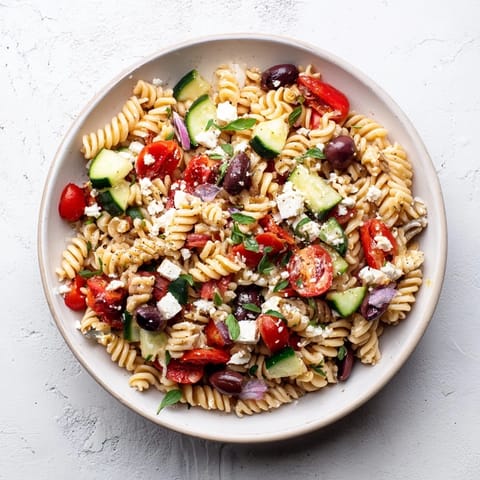 This Mediterranean Olive Oil and Feta Pasta Salad features crumbled feta atop a bed of pasta, ideal for lunch.