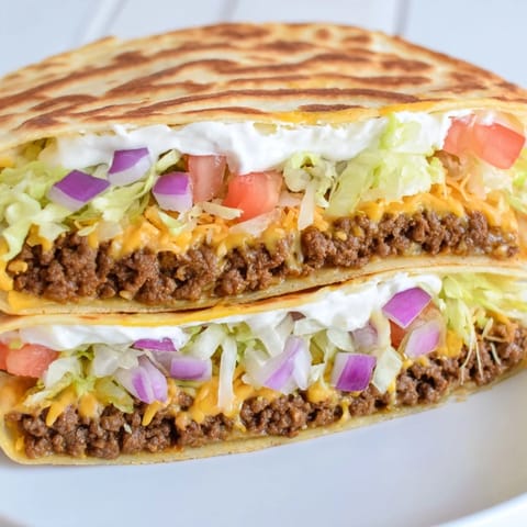 Golden-brown, crisp edges of a delicious Taco Bell Crunchwrap Supreme sit alongside fresh toppings.