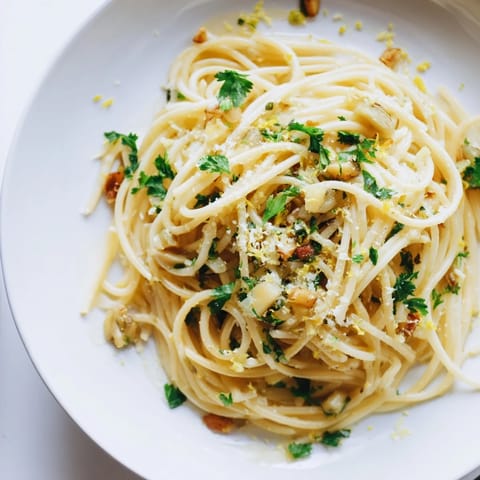 Close-up on a serving of Roasted Garlic & Asparagus Pasta, showing tender asparagus tips and caramelized garlic cloves mingling with al dente spaghetti.  
