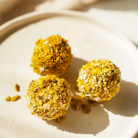 Golden no-bake Ginger Turmeric Energy Balls arranged on a parchment-lined tray, perfect for quick anti-inflammatory snacking.  