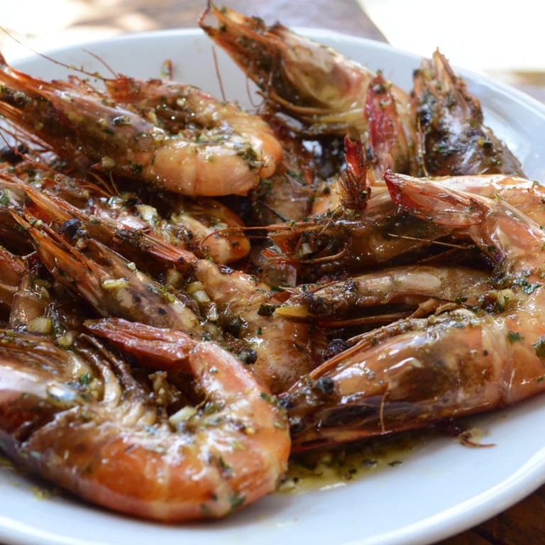 A close-up of steaming Lemon Herb Shrimp Scampi: shrimp coated in a bright, zesty lemon herb sauce.